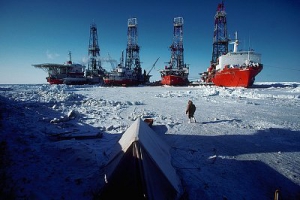 April 1980, Northwest Territories, Canada --- A man walks toward oil drilling ships in the pack ice on McKinley Bay with a tent in the foreground, Northwest Territories, Canada. --- Image by © Lowell Georgia/CORBIS